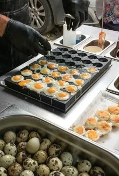 Frying  quail eggs on the stove in the bazaar. Stock Photos