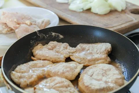 Frying Raw breaded chicken fillet on fry pan. Making dinner meal. Stock Photos