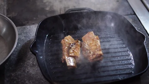 Frying raw slices of beef meat on hot steamy black grill pan in modern Stock-Footage 105896866