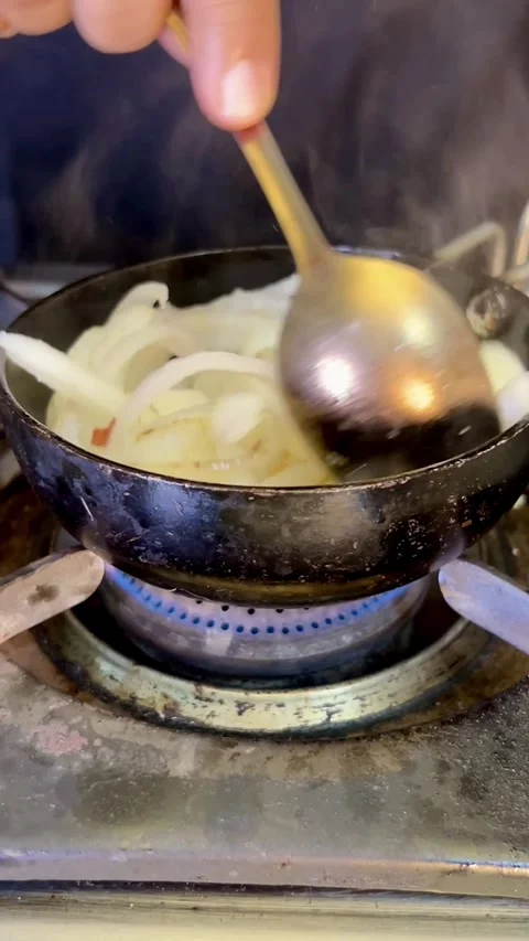 Frying root onion in a small frying pan on a stove. Stock Footage 286219323