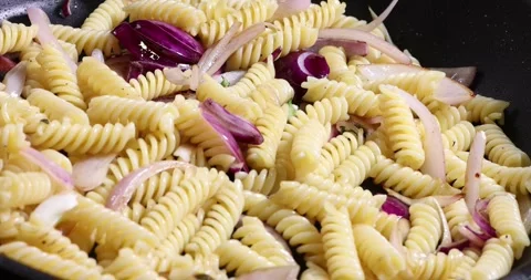 Frying sauteing fusilli pasta macaroni in non stick pan with olive oil slic.. Stock-Footage 267067816