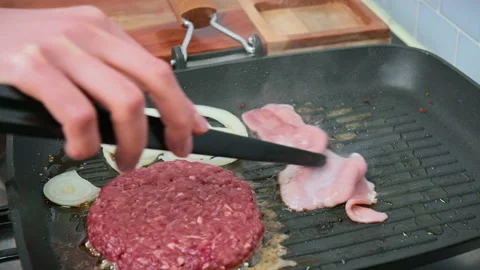 Frying a slice of bacon and burger ingredients on the grill in 4K. Stock Footage 153753292