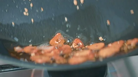Frying sliced garlic into a pan until golden crisp, making garlic chips in 4K. Stock Footage 141307302