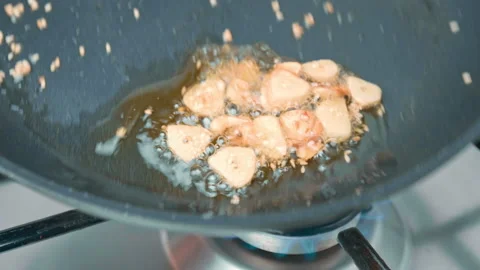 Frying sliced garlic into a pan until golden crisp, making garlic chips in 4K. Stock Footage 141307328