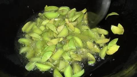 Frying Sliced Jengkol Beans in Hot Oil in a Black Wok Stock-Footage 310263936
