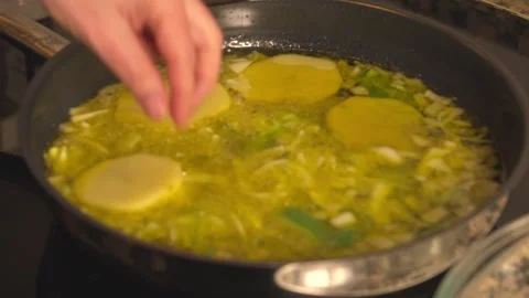 Frying sliced ​​potatoes with leeks in a pan with virgin olive oil Stock Footage 331313949