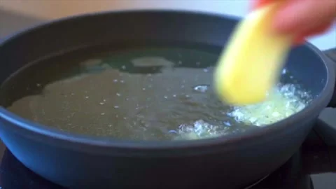 Frying sliced potatoes in oil to make a Spanish omelette (tortilla de patatas) Stock Footage 250566917