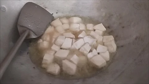 Frying Small Tofu Cubes in Hot Oil with Spatula Stock Footage 297027703
