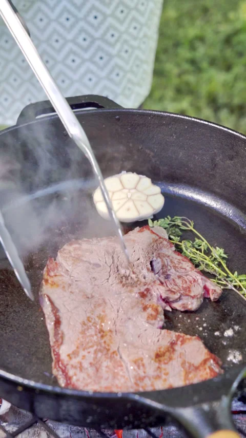 Frying steak in a cast iron. The chef flips the juicy steak to the other side. Stock Footage 315278077