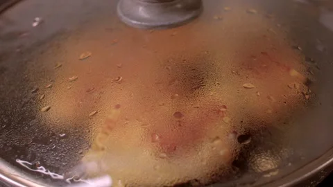 Frying succulent chicken thighs in a sizzling pan filled with bubbles and steam, Stock Footage 297202755