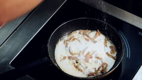 Frying tasty dish. Chef adding salt to bacon in sauce cooking in a frying pan. Stock Footage 236396864