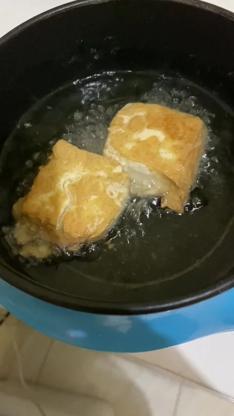 Frying tofu using an electric skillet Stock Footage 213611525