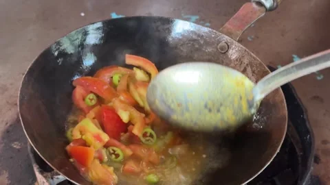 Frying tomatoes in a local frying pan at a desi Dhaba Stock Footage 296891424