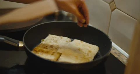 Frying tortilia wraps on a pan adding some seeds, covering with a lid Stock Footage 135242989