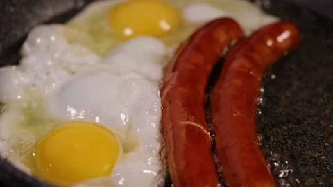 Frying two eggs and sausages in a lot of sunflower oil Stock Footage 171892378