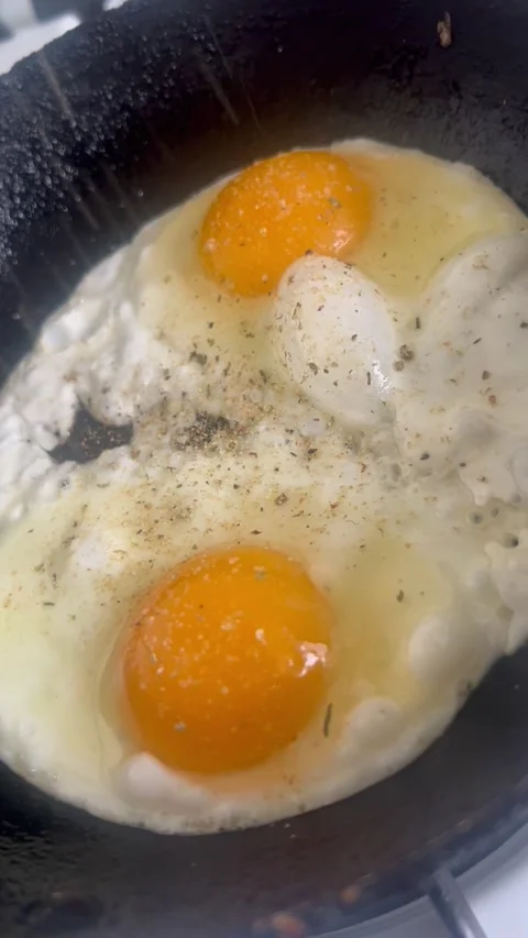 Frying Two Eggs with Salt and Pepper Stock Footage 308969007