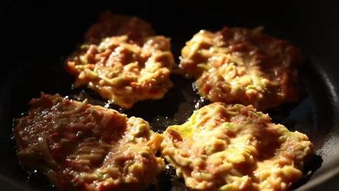 Frying vegetable pancakes with zucchini and carrots in a pan close up Stock Footage 345588753