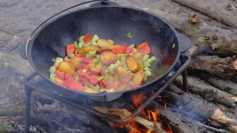Frying vegetables in a cauldron. Vegetables are fried in a cauldron over a fire Stock Footage 278868779