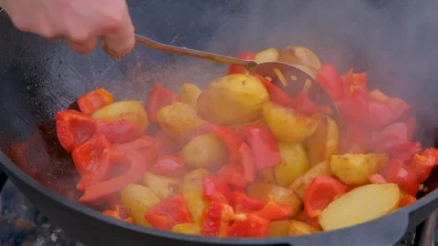 Frying vegetables in a cauldron. Vegetables are fried in a cauldron over a fire Stock Footage 279271635
