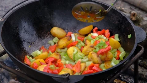 Frying vegetables in a cauldron. Vegetables are fried in a cauldron over a fire Stock Footage 280213863