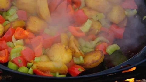 Frying vegetables in a cauldron. Vegetables are fried in a cauldron over a fire Stock Footage 280213870