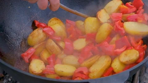 Frying vegetables in a cauldron. Vegetables are fried in a cauldron over a fire Stock Footage 280354741