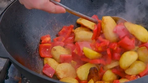 Frying vegetables in a cauldron. Vegetables are fried in a cauldron over a fire Stock Footage 280928647