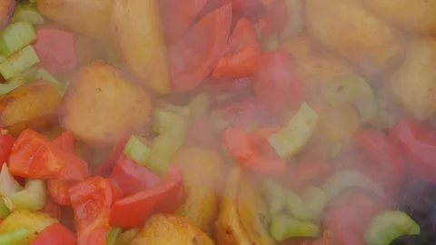 Frying vegetables in a cauldron. Vegetables are fried in a cauldron over a fire. Stock Footage 283630050
