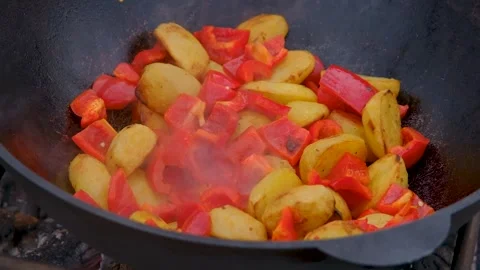 Frying vegetables in a cauldron. Vegetables are fried in a cauldron over a fire Stock Footage 284173461