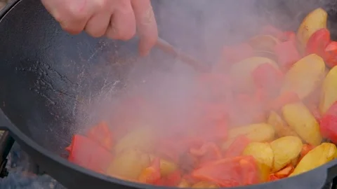 Frying vegetables in a cauldron. Vegetables are fried in a cauldron over a fire Stock Footage 284940339