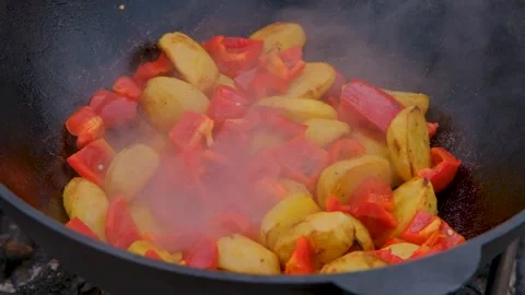 Frying vegetables in a cauldron. Vegetables are fried in a cauldron over a fire Stock Footage 309006634