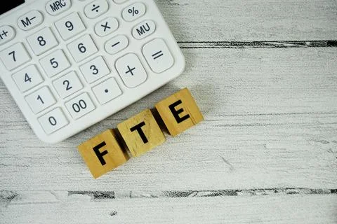 FTE (Full Time Equivalent) text with calculator on wooden background Stock Photos