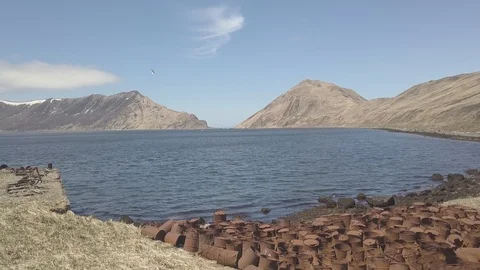 Fuel barrels at garbage dump on sea beach in old abandoned town drone view Stock Footage 98304950