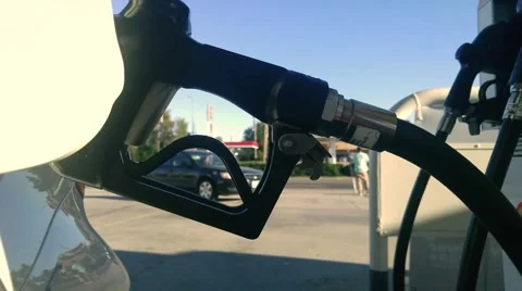 Fuel nozzle inserted in car gas tank as it's being refueled at gas station pump Stock Footage 67940894