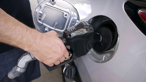 Fuel nozzle inserted in a car gas tank man hand holds the nozzle at gas station Stock Footage 77931939