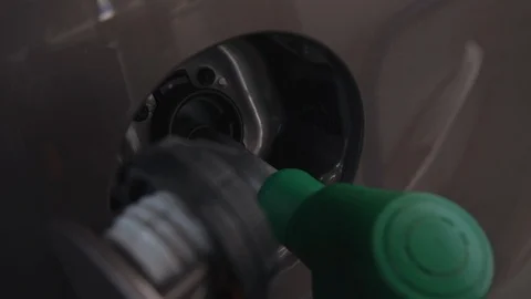 Fuel nozzle inserted into opened car tank during filling up at gas station. Video stock 119478810