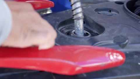 A fuel station worker inserts a fuel nozzle into a motorbike during refueling. D Stock Footage 341408498