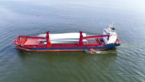 Full aerial view of red cargo ship carrying weather vane propeller, advancing Stock Footage 242760924