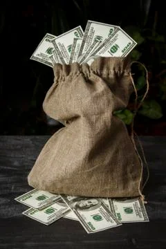 A full bag of dollars on a dark table Stock Photos