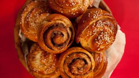 Full  basket of sweet bread rolls with cinnamon and sesame seeds  stop motion ov Stock Footage 72974120