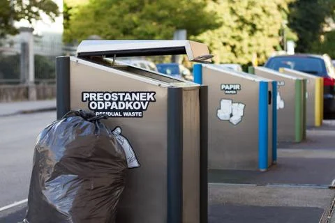 Full black garbage bag next to the open trash bin. Stock Photos