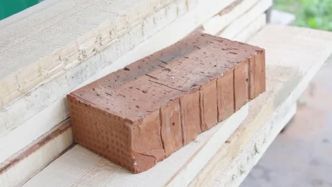 Full-bodied red building bricks in the hands of the worker Video stock 77198132