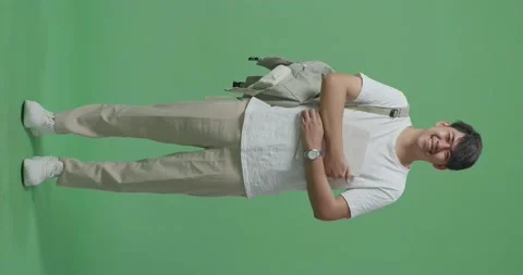 Full Body Of Asian Man Student Holding Book And Smiling To Camera On Green Stock Footage 220580153