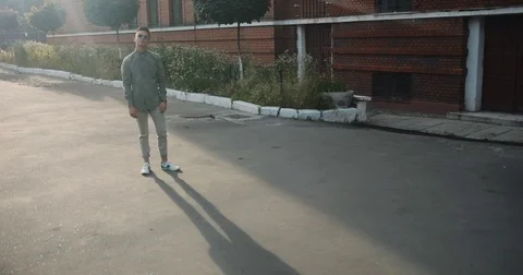 Full body stylish young man guy student street sunny day evening shadow lit Stock Footage
