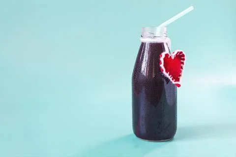 A full bottle with a dark liquid, a light tube and a red heart. Stock Photos