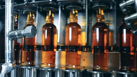 Full bottles with alcohol on a working machine at a factory. Whiskey, scotch Stock Footage 103263617