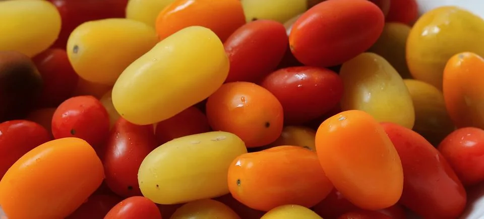 Full frame background of assorted red orange and yellow tomatoes Stock Photos