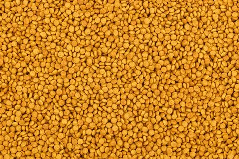 Full frame background an seamless texture of small dry orange cat food crockets 库存照片