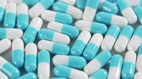 Full frame of blue and white capsules slowly rotating, close-up background Stock Footage 348209650