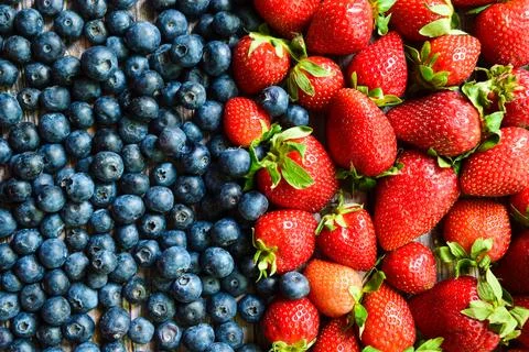 Full frame close-up of fresh ripe red strawberries and dark blueberries arranged Stock Photos
